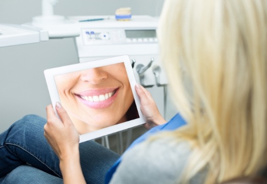 Woman looking at virtual smile design on tablet computer