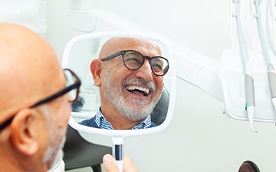 Man with glasses smiling at reflection in mirror