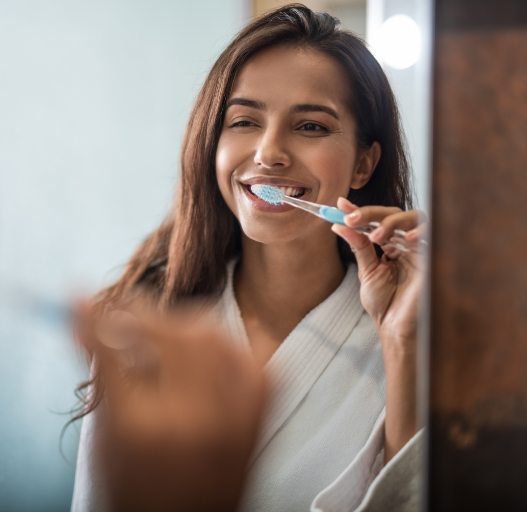 Woman brushing teeth to prevent dental emergencies