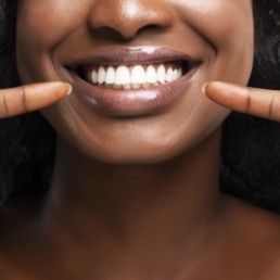 Woman pointing to healthy smile after periodontal disease treatment