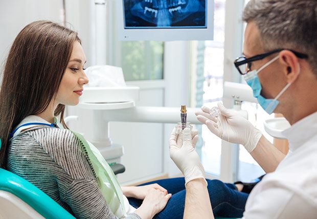 A dentist explaining the cost of dental implants in Warsaw