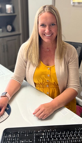 Smiling dental team member in Warsaw sitting at desk