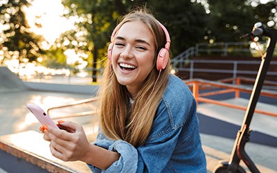 Teenage girl smiling while listening to music outside
