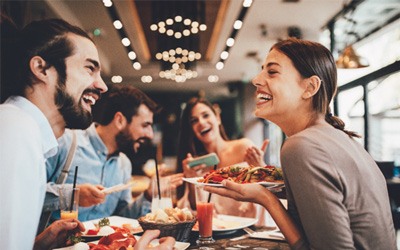 Group of friends smiling while eating at restaurant
