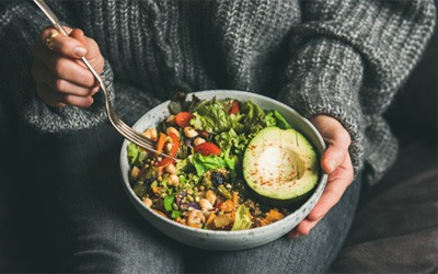 A person eating from a bowl of healthy foods