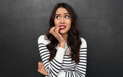 A brunette woman biting her nails 