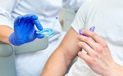 A dentist showing their patient a mouth guard  