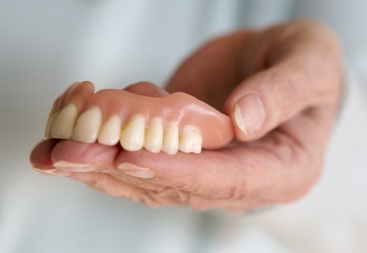 Hand holding full denture