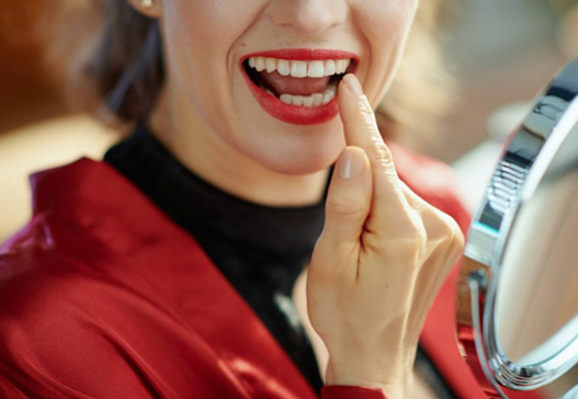 Woman smiling in mirror while pointing at her teeth