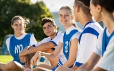 Teen athletes with full smiles after replacing missing teeth