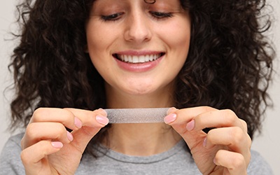 Woman using a teeth whitening strip