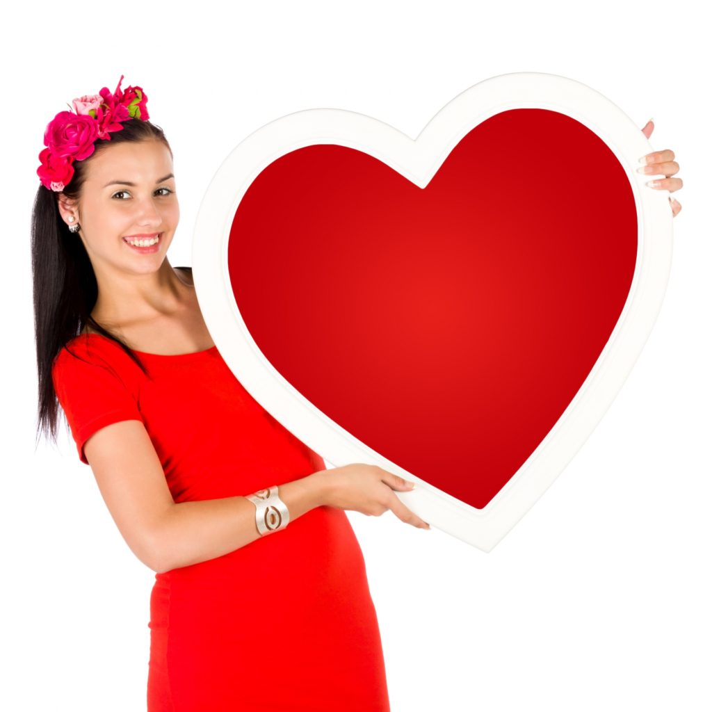 person smiling and holding up a paper heart