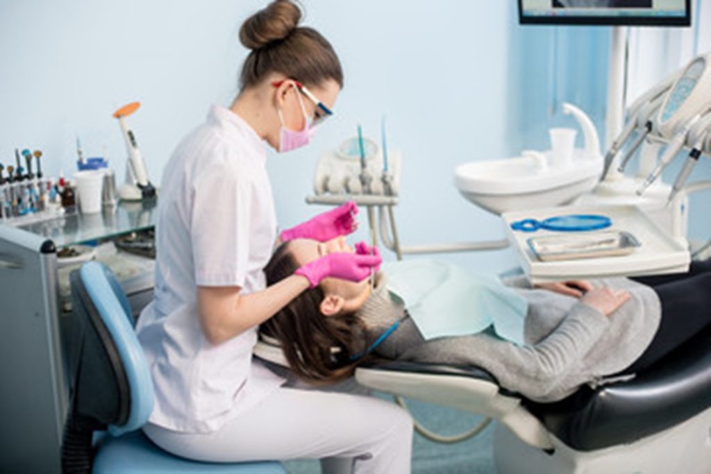 dentist performing oral cancer screening on patient