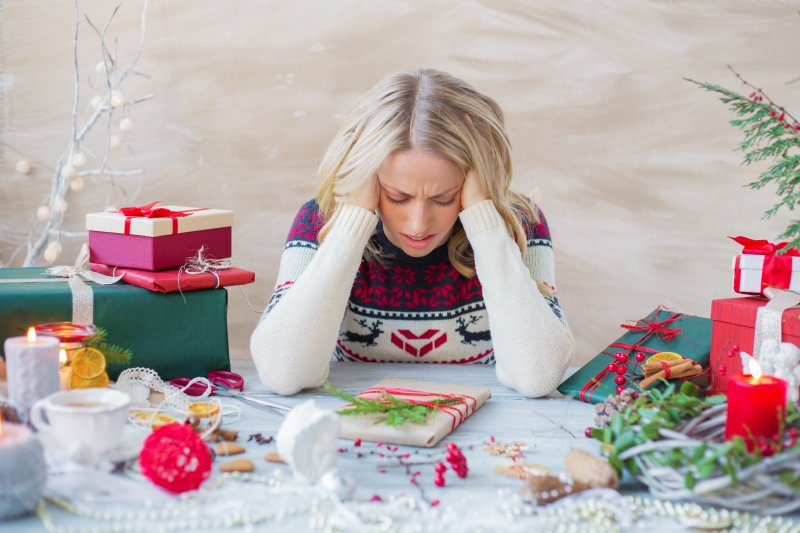 A stressed woman in a holiday sweater thinking about her dental health